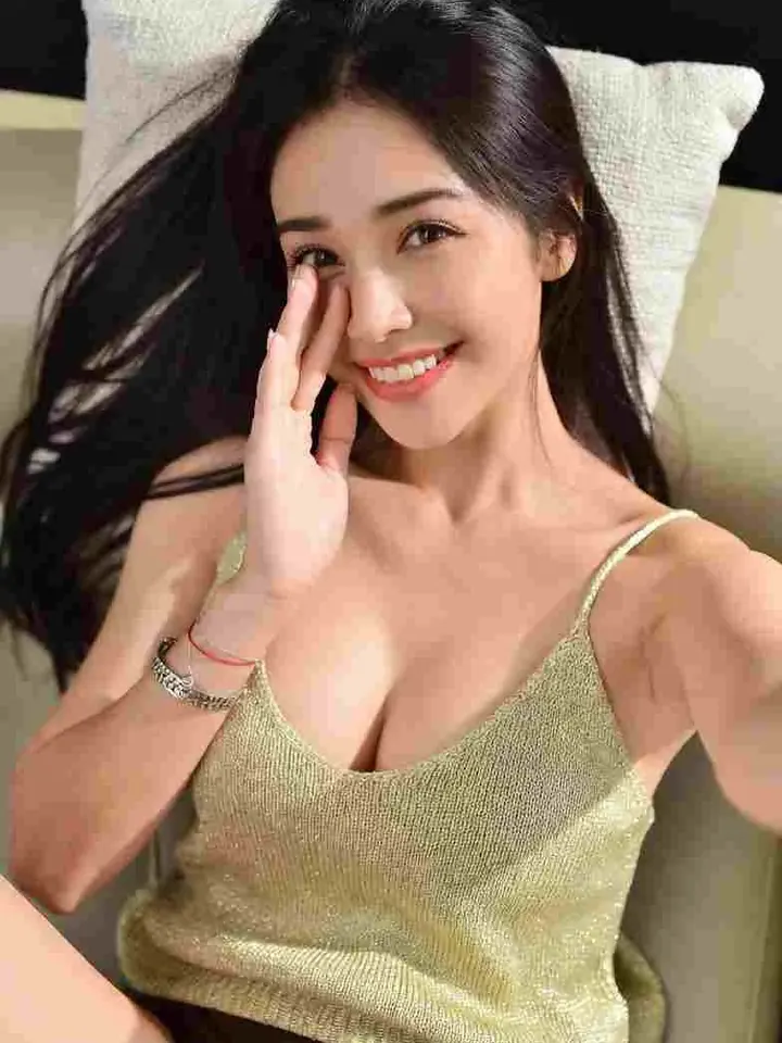 Warm black-haired AI girlfriend Maya smiling in a cozy bedroom